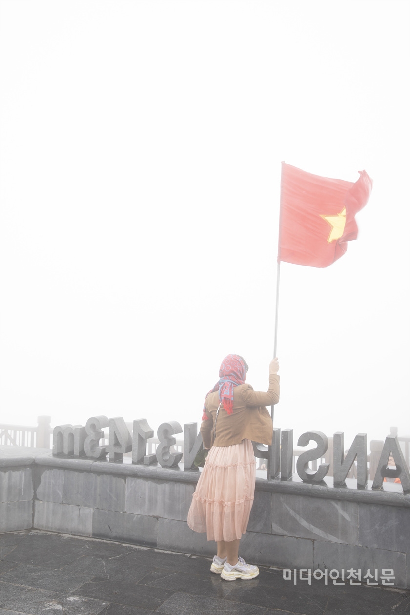 어느 한 관광객이 정상에서 베트남 깃대를 잡고 인증샷을 찍고 있다.