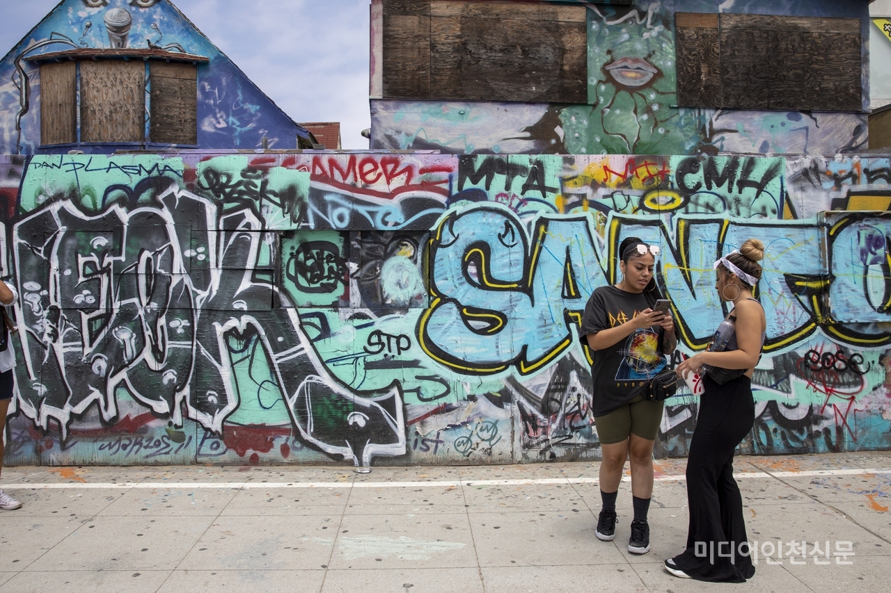 미국의 담장들을 아디를 가나 거리의 예술가 들이 그림들을 그려 놓아서 볼거리 등을 제공을 한다. 담장 앞에서 기념사진을 찍고 찍은 사진을 보고 있는 두 사람.