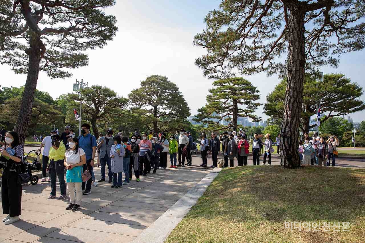 많은 사람들이 본관 앞에서 기념 촬영을 하기 위해 줄을 서있다.